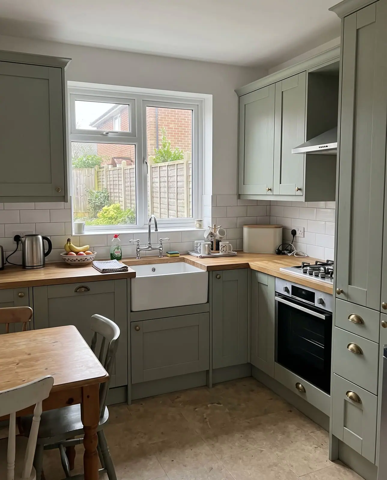 A sage green shaker kitchen with oak worktops and a Belfast sink