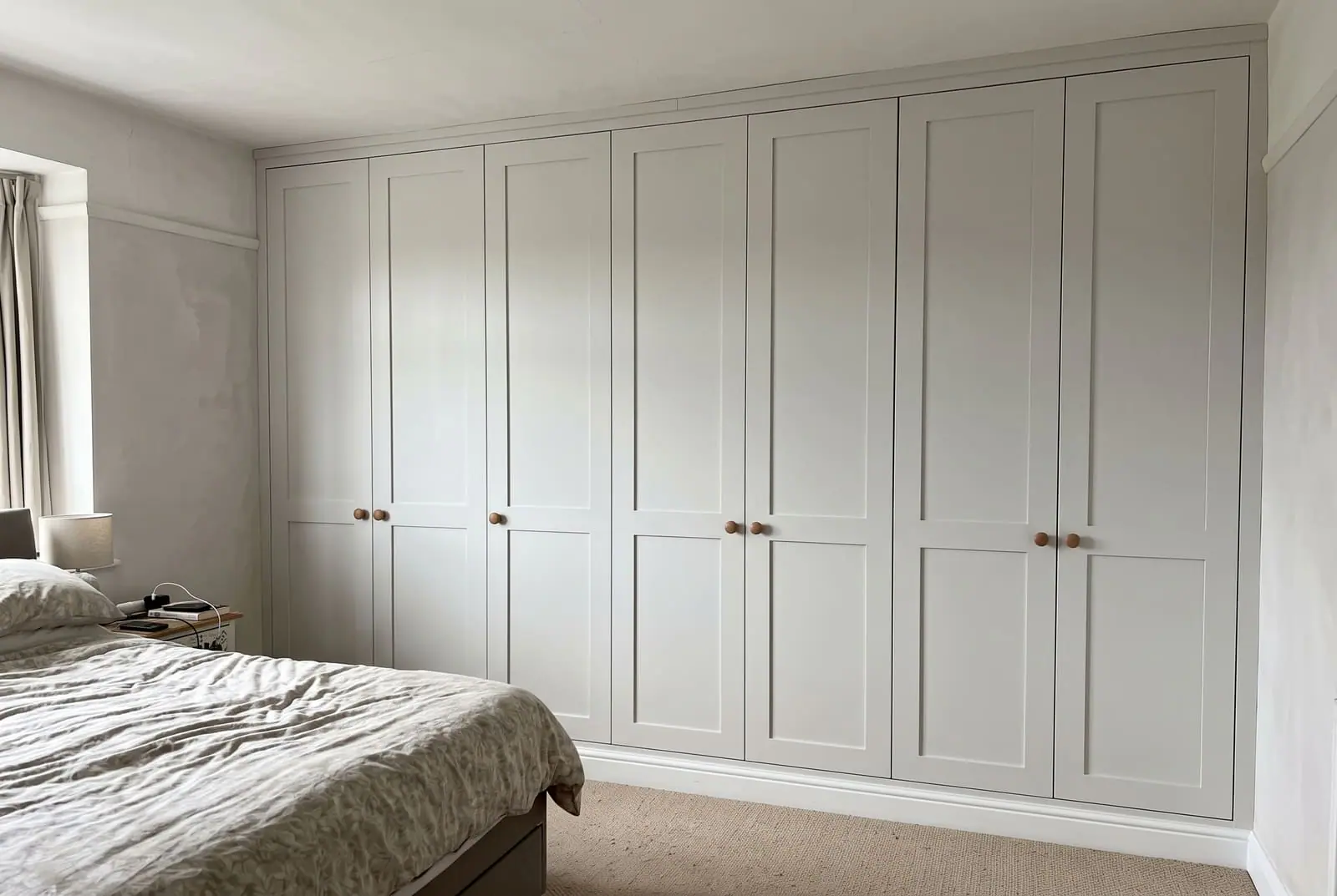 Painted fitted wardrobes running floor to ceiling in a bedroom